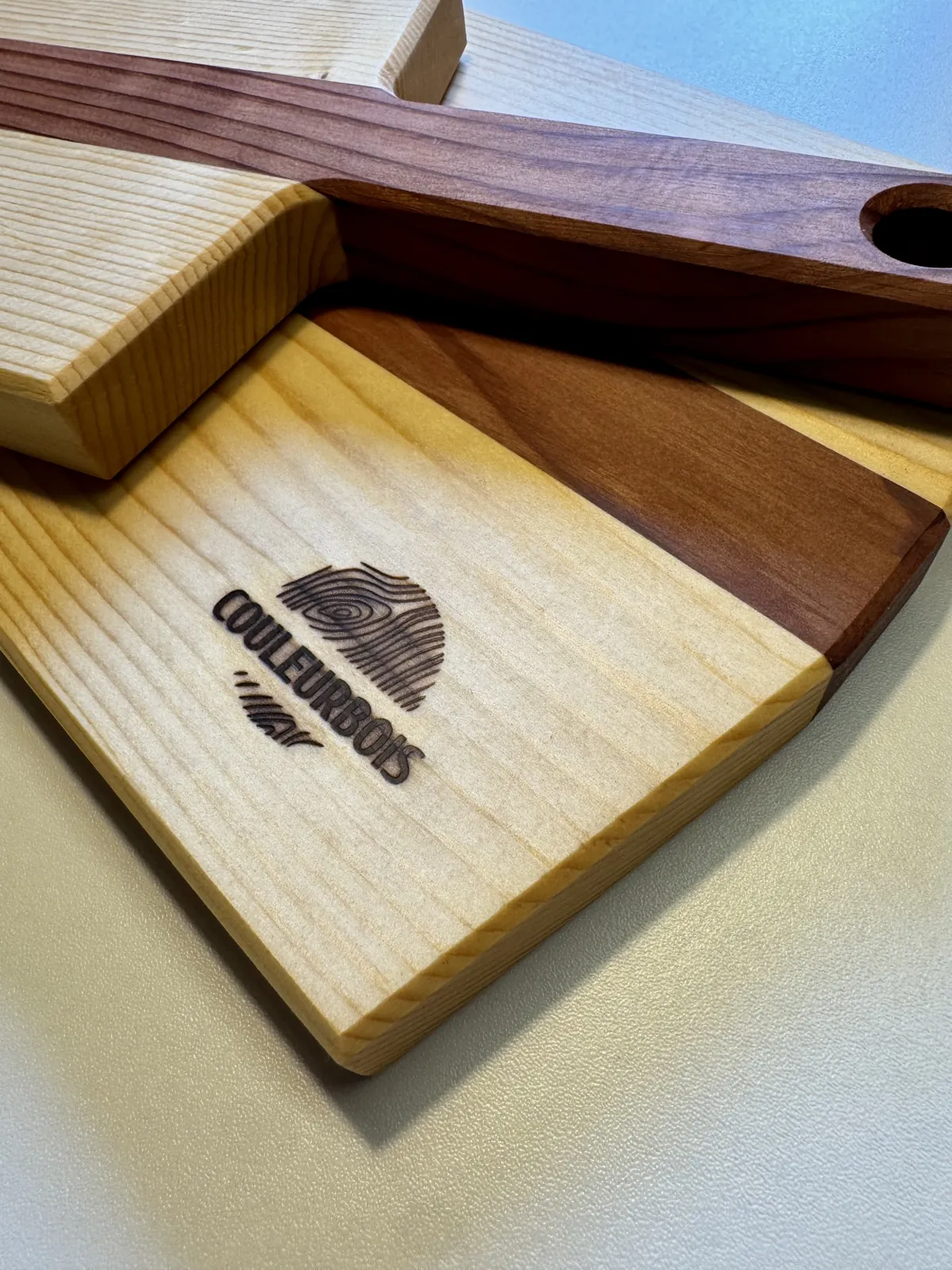 Planche de service en bois massif clair et foncé, manche percé et logo CouleurBois gravé au fer