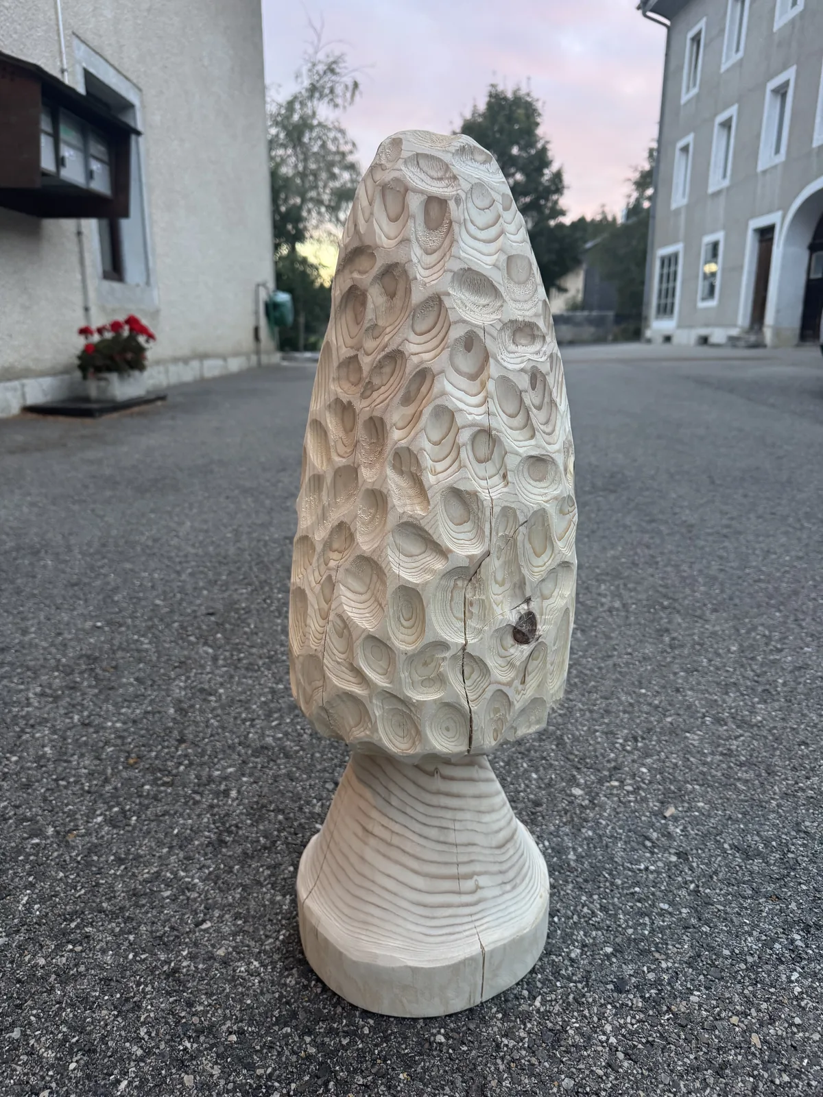 Sculpture sur tronc en bois clair gougée à la main, posée devant l'atelier du Solliat